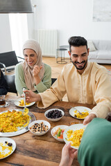 cheerful muslim woman laughing during dinner with family at home.