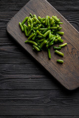 Green beans on wooden cutting board, low key photo with copy space