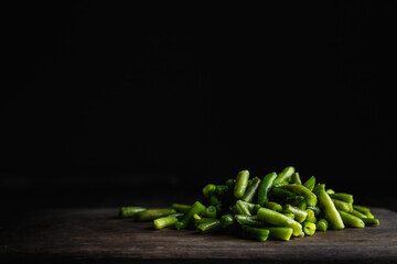Green beans on wooden cutting board, low key photo with copy space