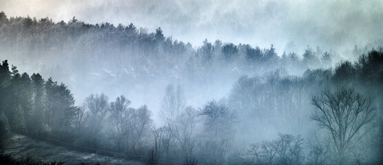 Landscape of frosty layers of hills covered in fog.