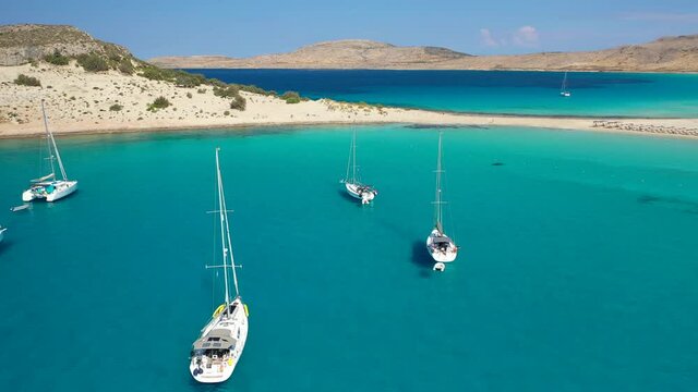 Aerial drone video of paradise turquoise sandy beach and bay of Simos in island of Elafonisos visited by yachts and sail boats, South Peloponnese, Lakonia, Greece