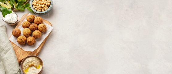 Traditional oriental chickpea deep fried falafel on a wooden board, tzatziki yoghurt sauce, hummus,...
