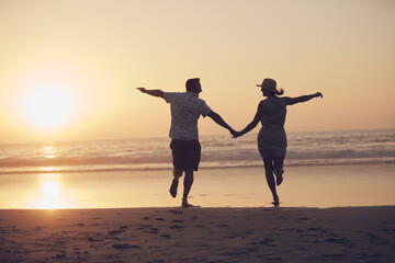 Fototapeta premium Off into the sunset they went. Shot of a mature couple running on the beach.