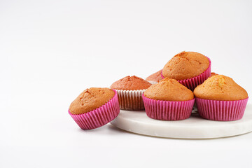 Several homemade white and pink muffins on marble board on white surface
