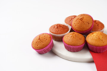 Several homemade white and pink muffins on marble board on white surface