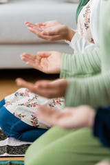Fototapeta premium Cropped view of blurred arabian women and kid praying at home.