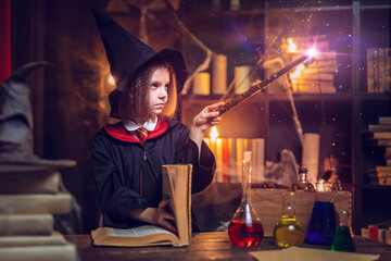 little witch makes a spell with a magic wand. Halloween party. Cosplay. Happy childhood