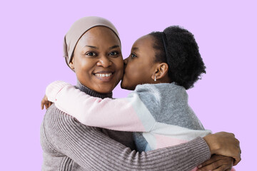 Charming african woman in headscarf smiling sincerely on camera while her pretty daughter gently...
