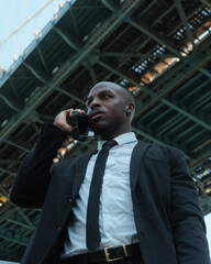 USA, New York City, Low angle view of man talking on smart phone under bridge