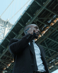 USA, New York City, Low angle view of man talking on smart phone under bridge