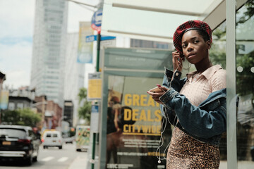 USA, New York, Stylish woman with smart phone on bus stop - obrazy, fototapety, plakaty