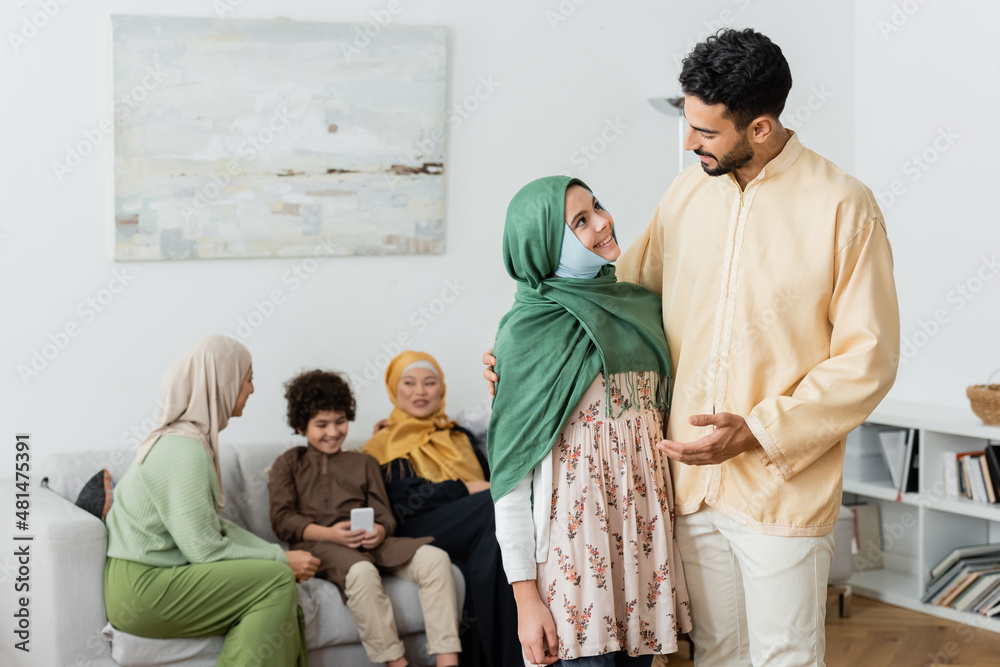 Wall mural arabian man talking to muslim daughter near multiethnic family on blurred background.