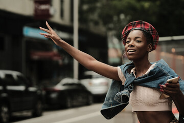 USA, New York, Smiling stylish woman hailing taxi on street