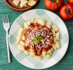 Italian pasta gnocchi on a plate with tomato sauce, basil and parmesan cheese