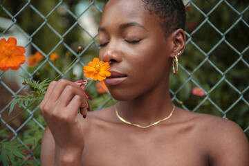 Close-up of woman smelling orange flower with eyes closed
