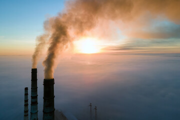 Obraz premium Aerial view of coal power plant high pipes with black smoke moving up polluting atmosphere at sunset