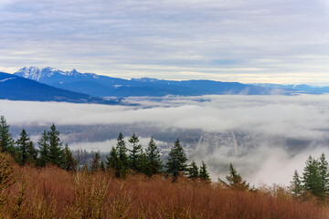 Fototapeta na wymiar Fraser Valley winter cloud inversion over Port Moody, BC, at Burrard Inlet with alpine mountain backdrop.