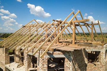 Aerial view of unfinished house with wooden roof frame structure under construction.