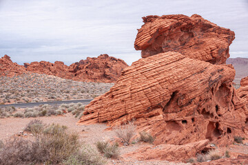 Overton, Nevada, USA - February 24, 2010: Valley of Fire. Lined and cracked figurative rock on top of other one on dry beige desert floor under thick gray cloudscape.
