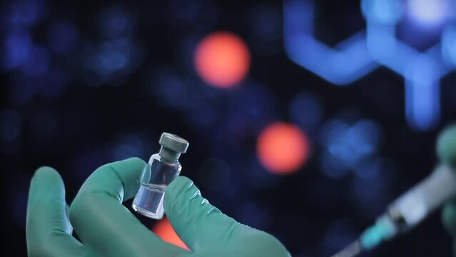Medicina en frasco cl&iacute;nico, manipulado por manos de cient&iacute;fico mientras en bokeh se ven de fondo luces. Jeringa