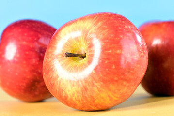 beautiful red apples seen from the side isolated on yellow and blue background, healthy natural fruit