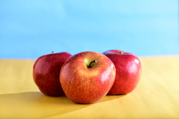 beautiful red apples seen from the side isolated on yellow and blue background, healthy natural fruit