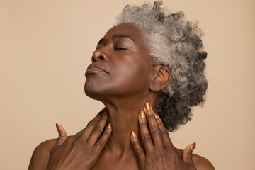 Studio shot of mature woman with eyes closed touching neck