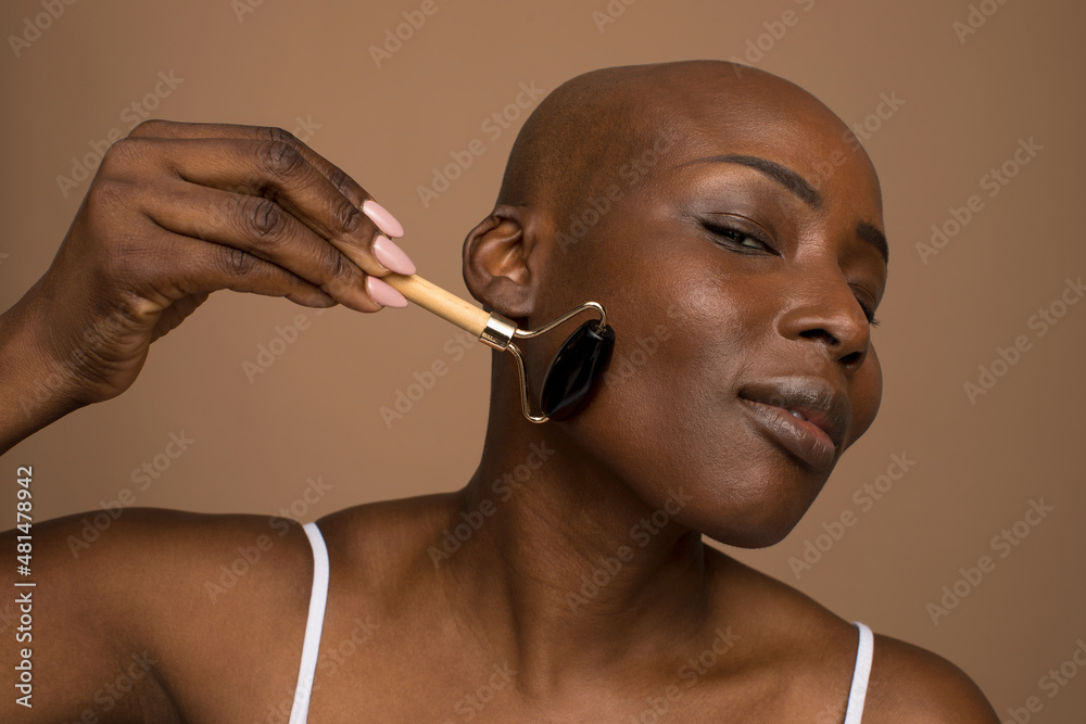 Sticker studio portrait of woman massaging face with stone roller