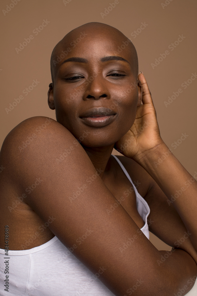 Wall mural Studio portrait of smiling woman with shaved head