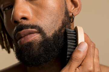 Close-up of young man brushing beard