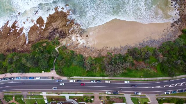 Horizontal static aerial view on crashing ocean waves and traffic on a road / Sunshine Cost Queensland