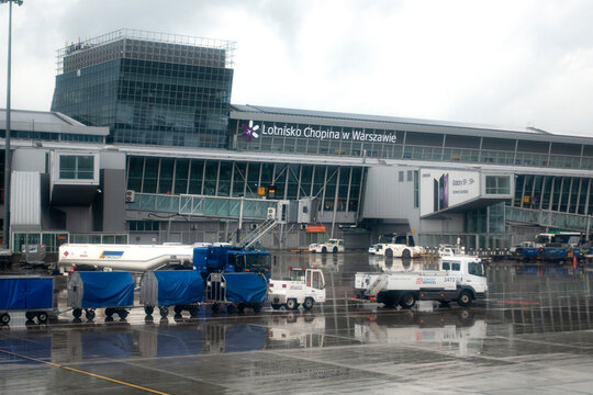 Warsaw-Chopin Airport with a chain of baggage carts on the  runway viewed from airplane window. Warsaw Poland