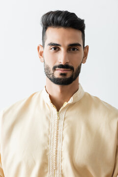 young bearded muslim man in traditional clothes looking at camera isolated on white.