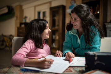 Mother helps daughter to do homework, real people in tracksuits in the garage at home