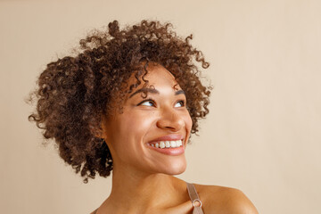 Cheerful multiracial woman posing against beige wall