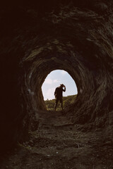 Portrait of a 30s man with a fedora and shirt at the entry of the Homer's cave