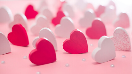 Fototapeta premium Lots of pink and white hearts on a light pink background. Love concept. Greeting card.Background of different colored wooden hearts.Valentine s day concept