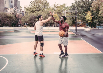 USA, Pennsylvania, Philadelphia, Men giving high five at basketball court in park