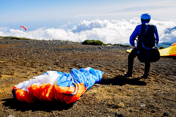 Skydiving experts and monitors prepare the sail of a paraglider to fly over the clouds of the...