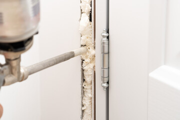 Spraying polyurethane foam from a gun to install and fix the interior door. - obrazy, fototapety, plakaty