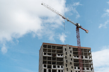 Tower crane lifting concrete panels at construction site during building construction.