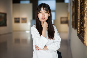 Portrait of chinese young woman near picture collection in the museum