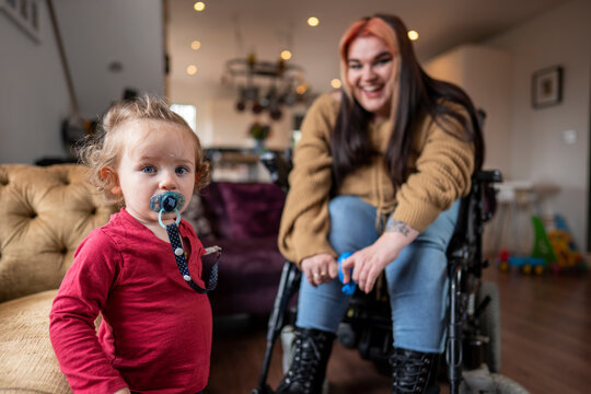 Smiling woman on wheelchair with baby son at home