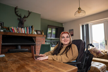 Woman in wheelchair working on laptop at home