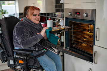 Woman in wheelchair putting cookies in over