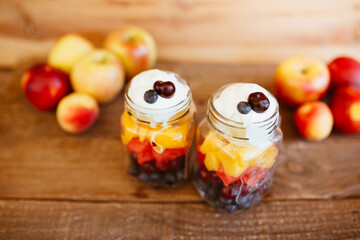 Fototapeta na wymiar Jars with chopped fruit salad. Mango, apple, grapes, blueberries and strawberries, with yogurt. Vegan and healthy food