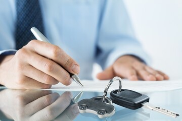 Car dealer businessman signing car insurance document. Car loan and insurance concept.