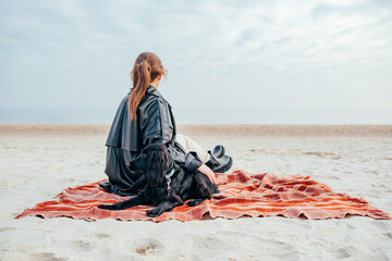 Rear view young woman sitting on beach with her dog