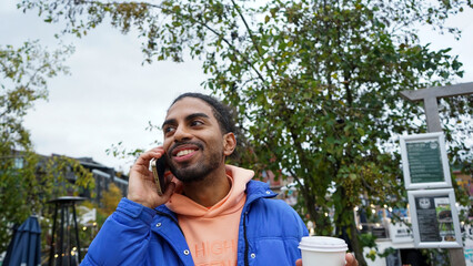 Young man holding coffee and talking on phone