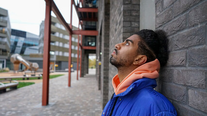 Young man wearing blue puffer jacket leaning on wall